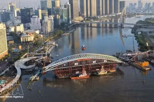 西贡河步行桥项目合龙作业现场全景，装载主跨结构的驳船已就位。（图片来源：越通社）
