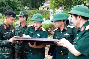 顺化市军事指挥部副政委河文爱大校（左三）在地图上确定烈士安葬位置。（图片来源：越通社）