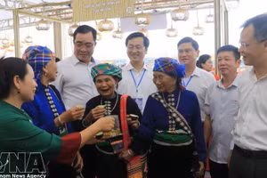 代表们与当地居民在博览会上品茶。（图片来源：越通社）
