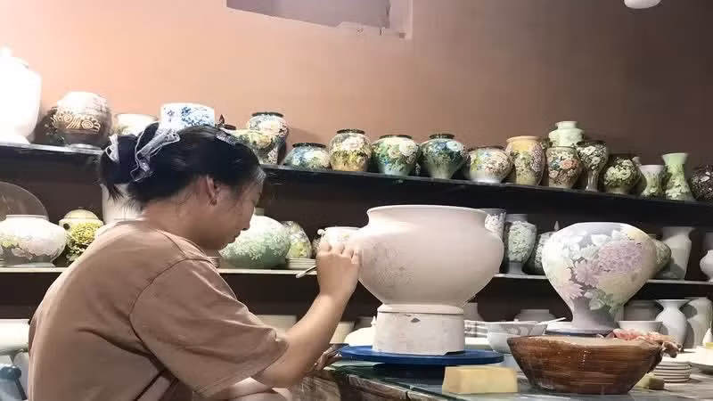 河内市钵场乡的陶瓷作坊在陶器上绘制图案。（何英 摄）