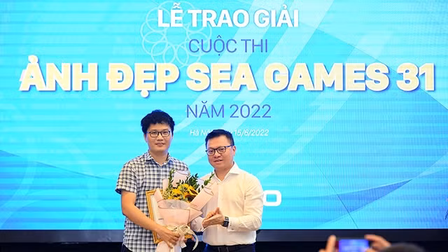 《人民报》社总编辑黎国明向获得一等奖的摄影师张英德颁奖。