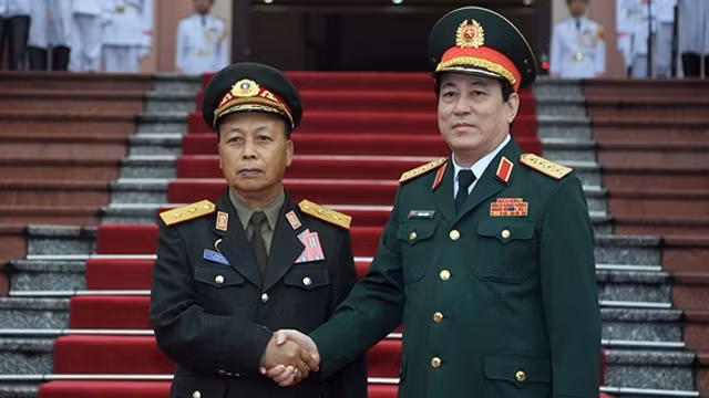 越南人民军总政治局主任梁强与老挝人民军总政治局主任通莱·西力冯握手。