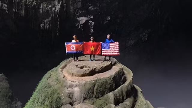 游客手拿着朝鲜、越南和美国国旗在韩松洞照相。
