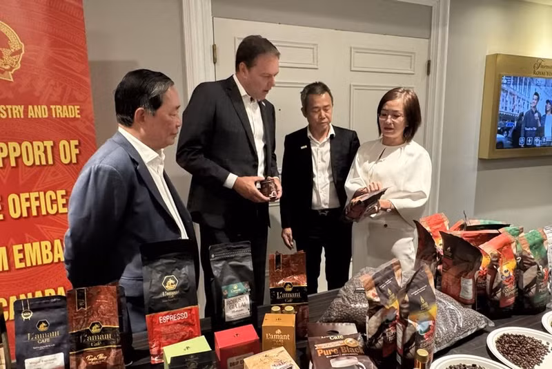 越南驻加拿大商务参赞陈秋琼向加拿大咖啡协会主席罗伯特·卡特介绍越南咖啡。（图片来源：越通社）