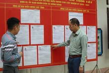 越南谅山省同登边境乡南关村党支部党员，在候选人名单公示处进行宣传与指导。