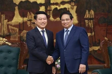 越南政府总理范明正与老挝副总理、人民革命党中央企业改革委员会主任沙伦塞·贡马西合影。