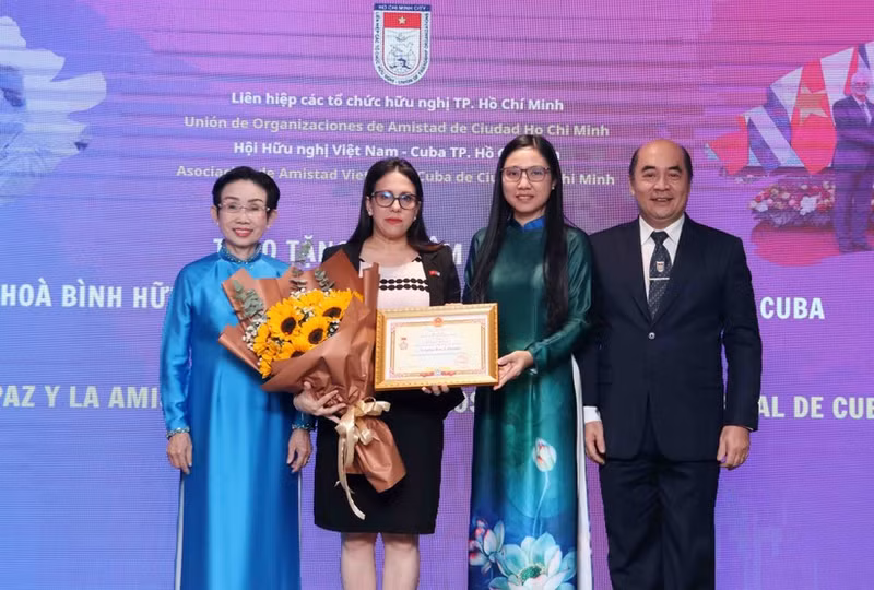 胡志明市友好组织联合会主席何清向古巴驻胡志明市总领事阿里亚德娜·费奥·拉布拉达颁授“致力于各民族和平友谊”的纪念章。