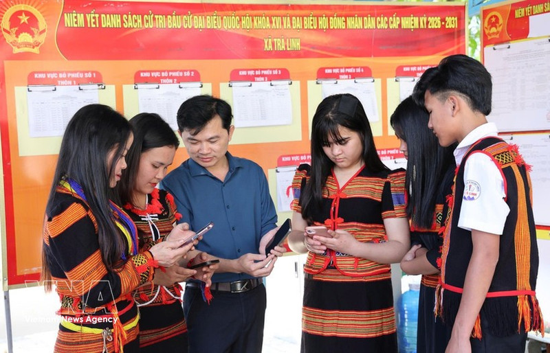 岘港市茶灵乡色当族同胞正在用手机查看有关第十六届国会及各级人民议会代表选举的视频和图表新闻，了解投票流程。