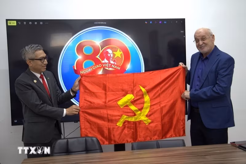 越南驻以色列大使李德忠向以色列共产党政治局委员、哈达什阵线主席伊萨姆·马库尔赠送党旗。