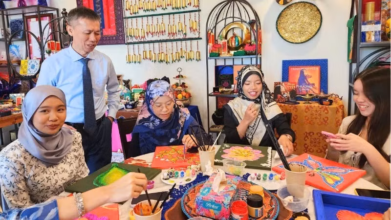 陈重义博士与文莱达鲁萨兰国国立大学学生共同体验越南与文莱传统图案装饰活动。（图片来源：越南驻文莱大使馆提供）