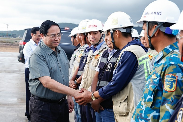 范明正总理与富国国际机场项目一线工作人员亲切握手。（图片来源：政府门户网）