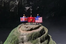 游客手拿着朝鲜、越南和美国国旗在韩松洞照相。