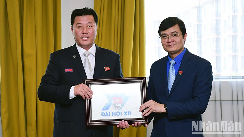 裴光辉同志向文哲同志赠送纪念品。