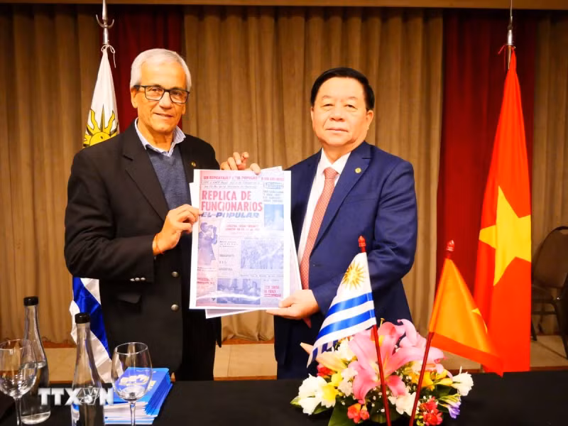 乌拉圭共产党总书记胡安·卡斯蒂略向越共中央宣教部部长阮重义赠送乌拉圭《人民报》发表的一篇讲述胡志明主席1920年访问蒙得维的亚的文章。（图片来源：越通社）