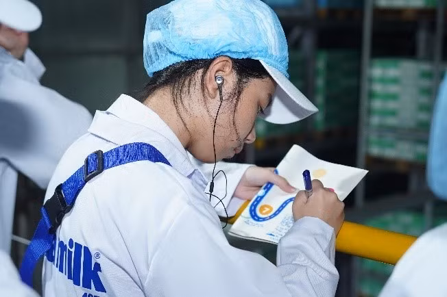 学生们集中倾听，认真记下在Vinamilk超级工厂制作一盒牛奶的生产流程。