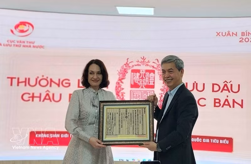 越南国家文书与档案局局长邓青松向俄罗斯驻越大使夫人埃琳娜·贝兹德特科赠送一幅越南国号的木刻版画。（图片来源：越通社）