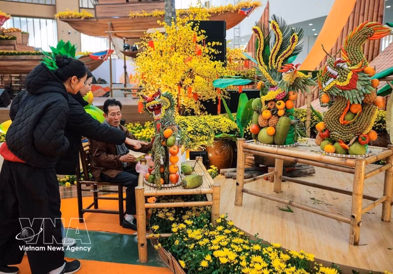 众多市民前来参观了解艺术家阮文线（胡志明市）创作的果蔬艺术雕刻作品。（图片来源：越通社）