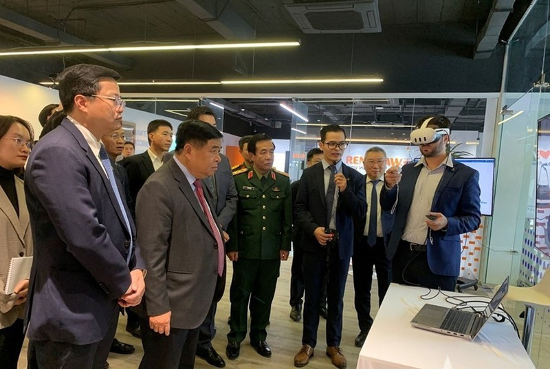 政府副总理阮志勇和其他代表听取关于人工智能与数字孪生研发中心及卓越中心的报告。（图片来源：人民军报网）