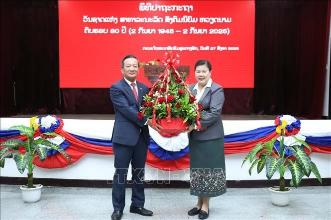 老挝人民革命党中央宣训部副部长薇拉翁·潘塔冯向越南驻老挝大使阮明心送花。（图片来源：越通社）