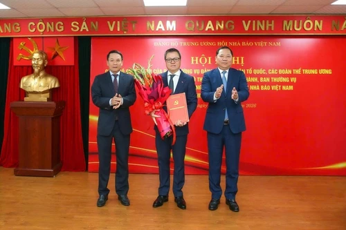 任命黎国明同志（中）为越南新闻工作者协会中央党委书记。