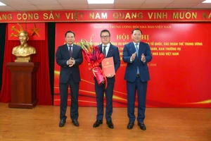 任命黎国明同志（中）为越南新闻工作者协会中央党委书记。
