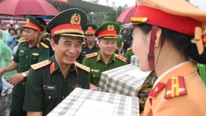国防部部长潘文江大将在综合演练上向参加阅兵、游行的各方力量赠送纪念品。