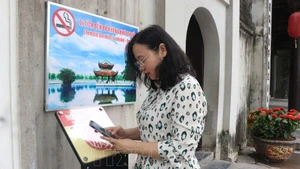 游客扫描二维码，体验在都祠遗迹实现数字化的参观行程。（图片来源：越通社）