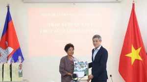 越南驻柬埔寨大使阮明宇向曾为抗美战争作出贡献、并于2009年荣获越南总理颁发的功绩证书的何氏娥女士赠送春节慰问品。（图片来源：越通社）