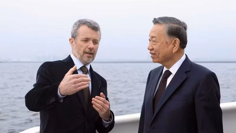 在乘船前往利奈特霍尔姆岛途中，丹麦国王腓特烈十世向越共中央总书记、国家主席苏林介绍利奈特霍尔姆人造岛项目。（图片来源：越通社）
