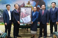 岘港市委常务副书记阮廷永和《人民报》社中部-西原地区分社代理社长潘泰山将胡志明主席阅读《人民报》的照片赠送给阿速坡省领导。（樱桃 摄）