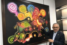 萨尔瓦多驻越南大使鲁本·奥马尔·奥罗斯科·布尔戈斯向各位代表介绍绘画作品。