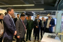 政府副总理阮志勇和其他代表听取关于人工智能与数字孪生研发中心及卓越中心的报告。（图片来源：人民军报网）