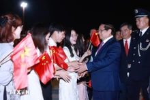 旅居中国越南人代表前来机场迎接越南政府总理范明正一行。（图片来源：越通社）