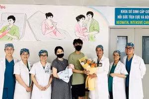 岘港妇产儿科医院医护人员向即将出院的一家三口赠送鲜花表示祝贺。