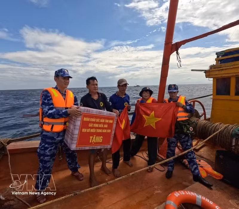 海警二区司令部的干部战士向渔民赠送国旗和慰问品，鼓励他们安心出海、扎根海上作业，严格遵守水产捕捞相关规定。（图片来源：越通社）