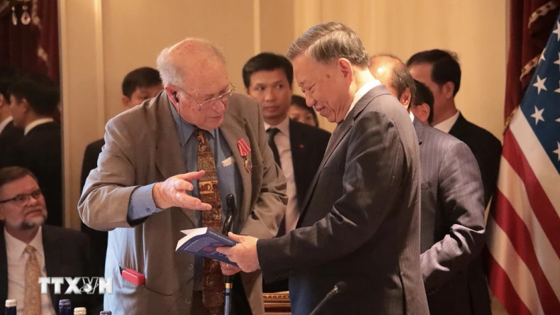 和解与发展基金会主席约翰·麦考利夫向越共中央总书记、国家主席苏林赠送有关越南的书籍。（图片来源：越通社）