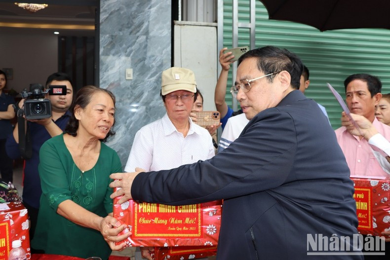 范明正总理向同奈省龙城县禄安-平山安置区人民赠送礼品。