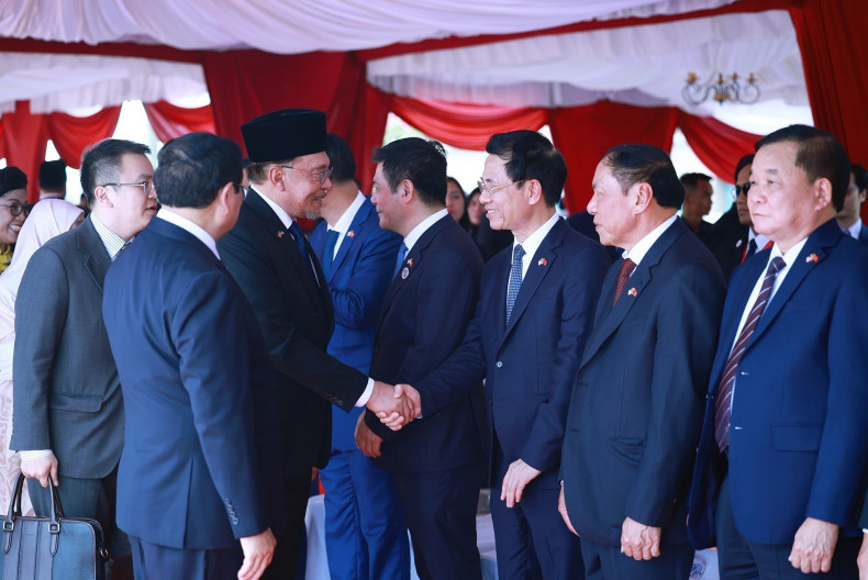 范明正总理向安瓦尔·易卜拉欣总理介绍越南代表团成员。