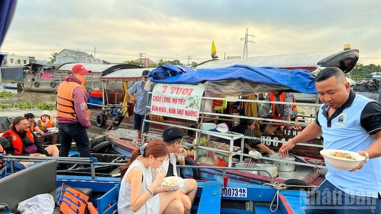 游客品尝丐冷水上集市美食。