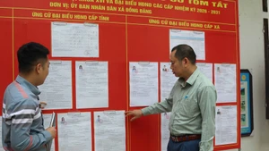 越南谅山省同登边境乡南关村党支部党员，在候选人名单公示处进行宣传与指导。