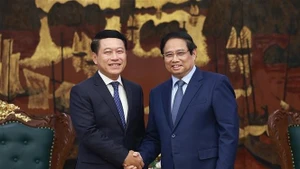越南政府总理范明正与老挝副总理、人民革命党中央企业改革委员会主任沙伦塞·贡马西合影。