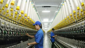 3·8纺织公司工人正在操作纱线生产线。（陈海 摄）