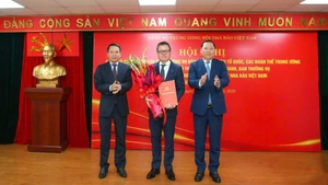 任命黎国明同志（中）为越南新闻工作者协会中央党委书记。