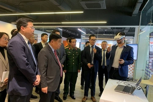 政府副总理阮志勇和其他代表听取关于人工智能与数字孪生研发中心及卓越中心的报告。（图片来源：人民军报网）