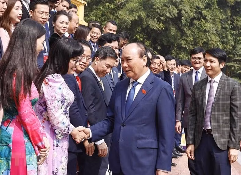 国家主席阮春福与模范青年企业家握手。
