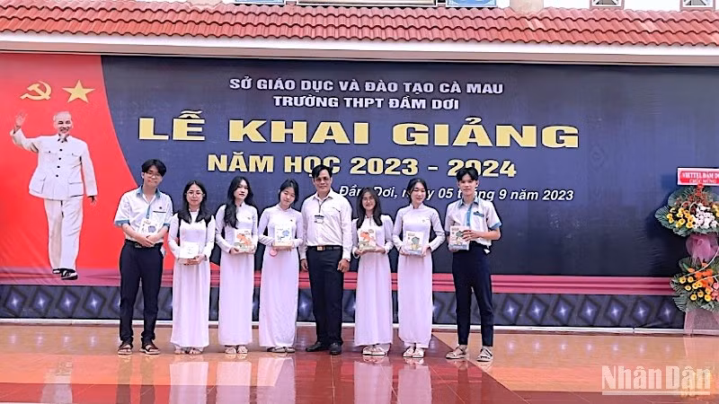 登瑞高中学校校长向学生赠送笔记本。
