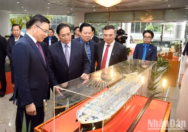 越南国家油气集团总经理黎孟雄向范明正总理介绍服务于越南石油和天然气活动的船舶模型。
