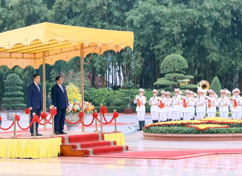 范明正总理和洪玛奈首相登上检阅台，军乐团奏响两国国歌。（图片来源：越通社）