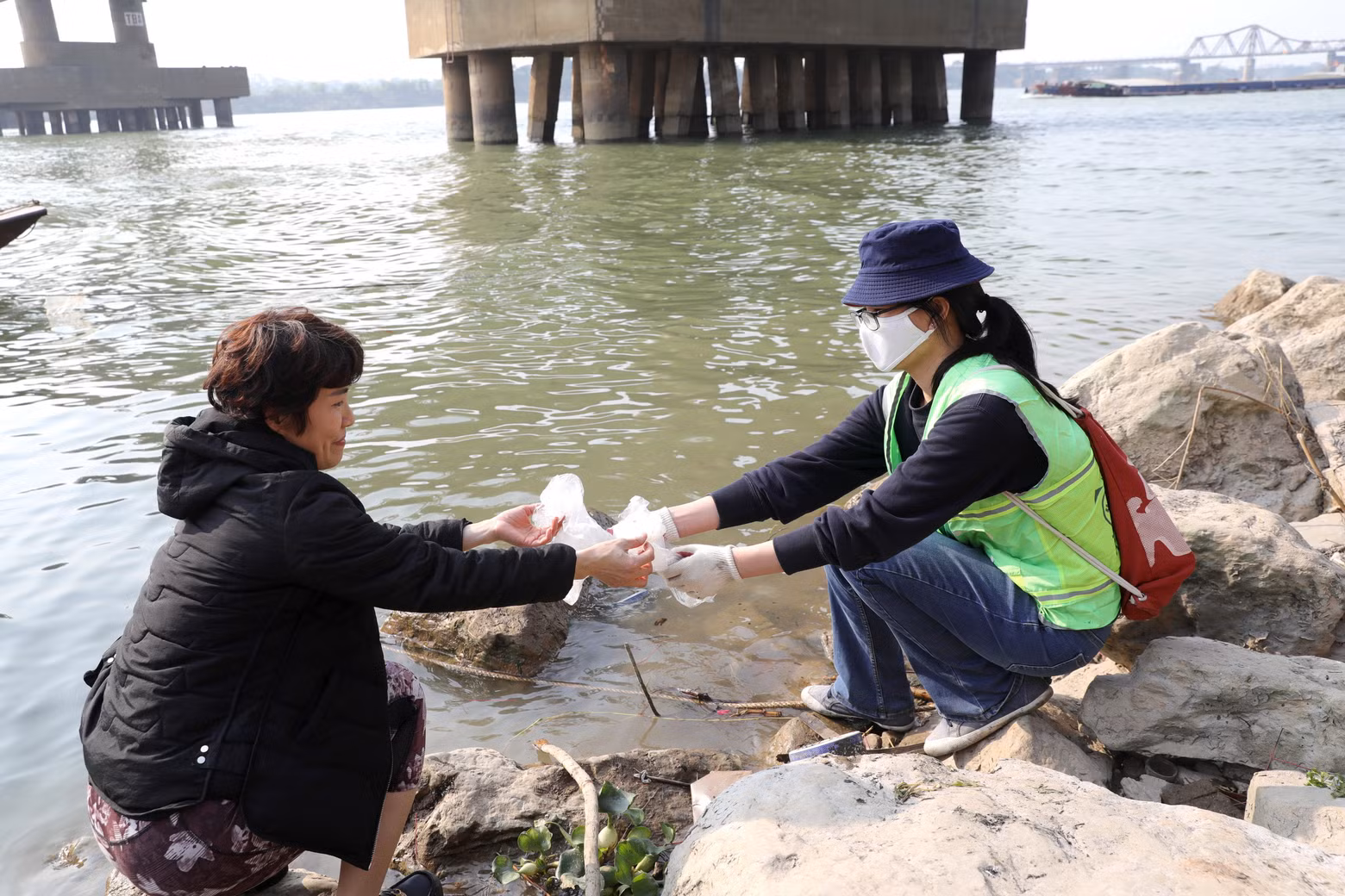 人民放生鲤鱼后把塑料袋交给越南保洁队成员。