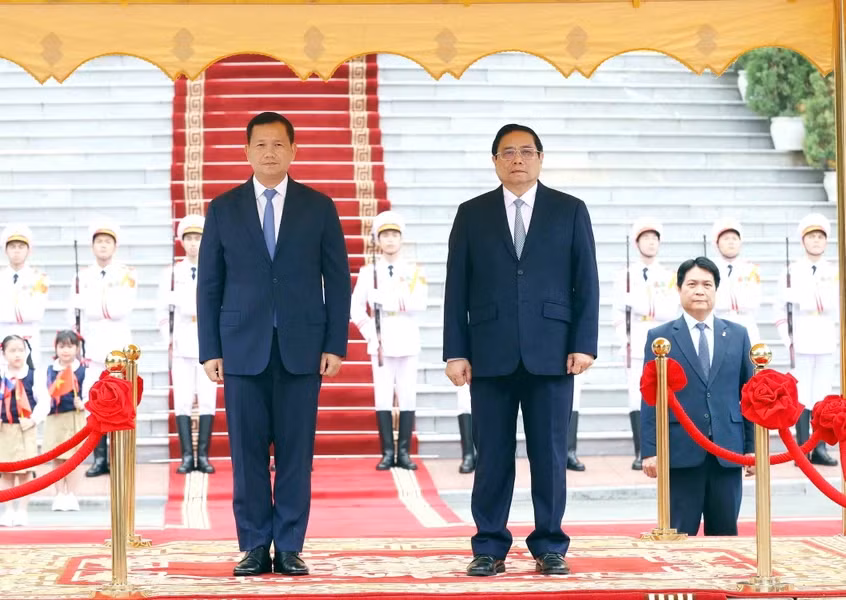 范明正总理和洪玛奈首相登上检阅台，军乐团奏响两国国歌。（图片来源：越通社）